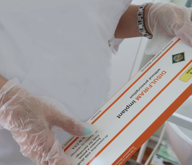 Врач держит в руках упаковку Дисульфирама